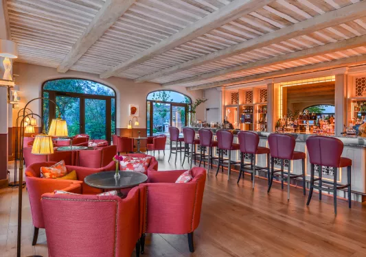 Bar and lounge filled with red cushioned chairs and stools