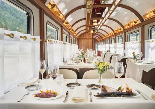 Dining area within a train, with tables and plates of food on top