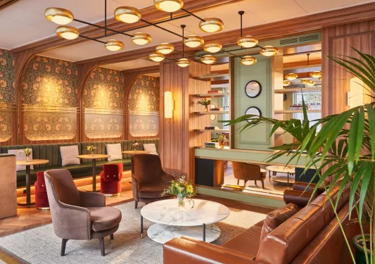 Lounge with wooden walls and cushioned sofas and chairs around circular tables