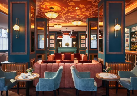 Blue lounge room with red and blue cushioned chairs and large light fixtures