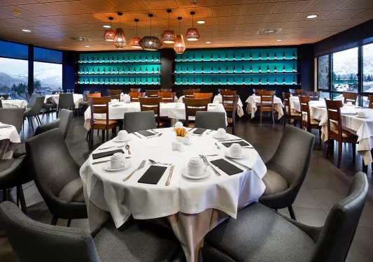 Indoor bar and dining area with black and wooden chairs, with bottles of alcohol along the wall