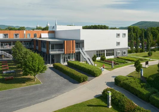 Exterior view of a gray stone building, with wooden accents and trimmed bushes in the front