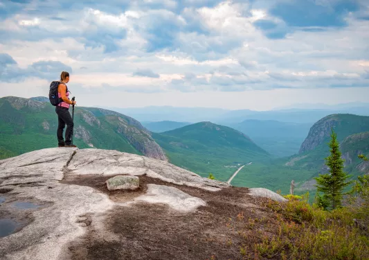 Woman at the top of a rock looking down at grassy hills