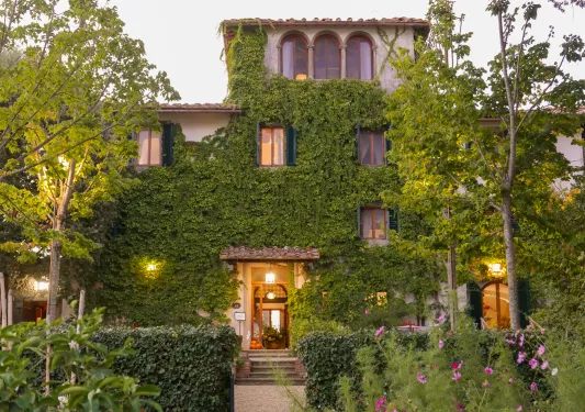 Exterior view of two-story building covered in plants and moss