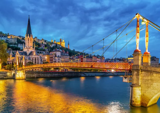 Illuminated suspension bridge leading to a rustic town