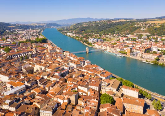 Brown and white buildings connected by a single bridge over a river