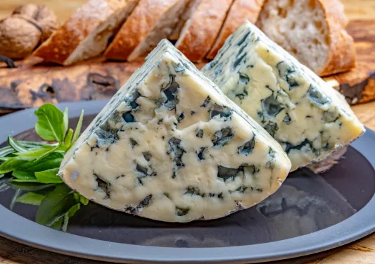 Plate of two slices of bleu cheese and slices of bread in the background