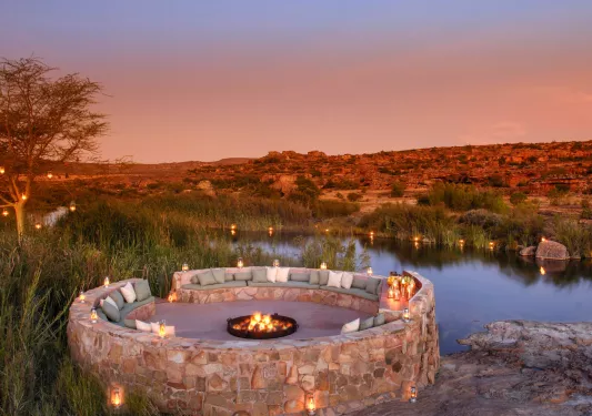 A circular seating area with a fire pit in the center, overlooking mountains and canyons
