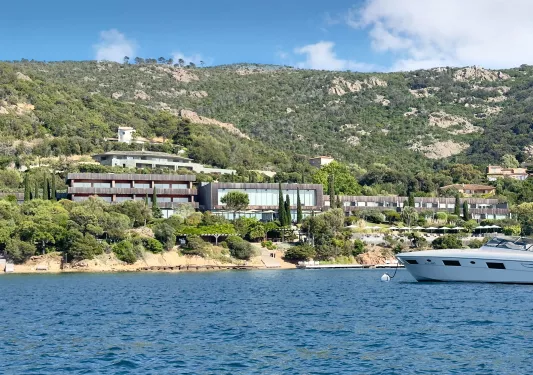 External view of gray building with a yacht in the ocean in front