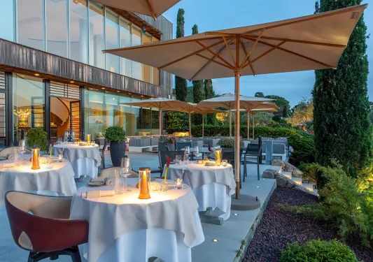 Outdoor patio and dining area, with large umbrellas and candles on each table