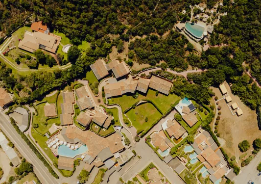 Sky view of tan colored buildings, surrounded by trees and minim outdoor pools