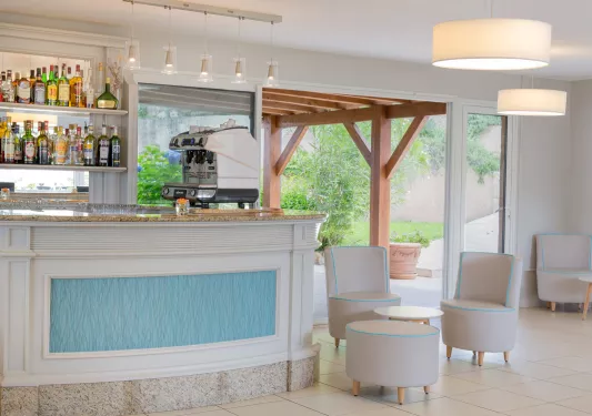 Bar with liquor on the wall and circular tables and chairs to the right