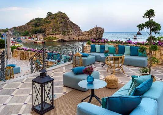 Outdoor patio with blue, cushioned chairs, looking out towards the ocean