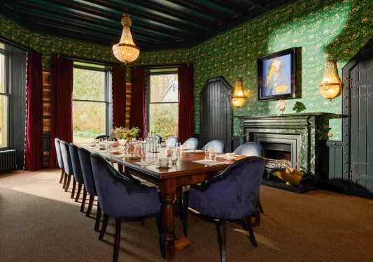 large dining room table next to fireplace in wallpapered room