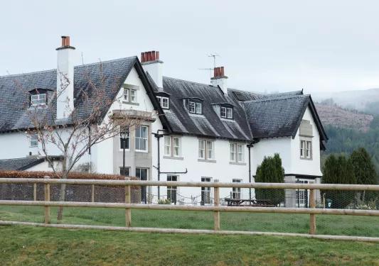 White cottage-style building with a black roof and an open grass area in front