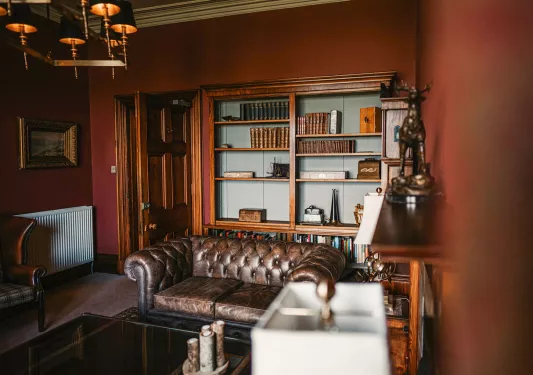Leather couch in a library room with antiques on the wall