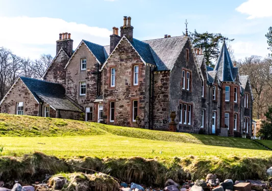 Rustic, brown brick building with an open grass area in front