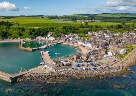 Brown buildings next to a small lake with a pier full of boats