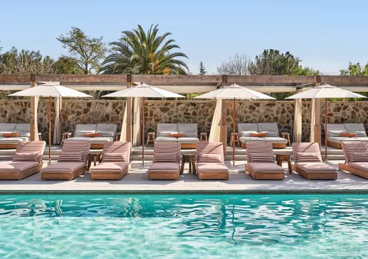 Outdoor pool with cushioned pool chairs and white umbrellas