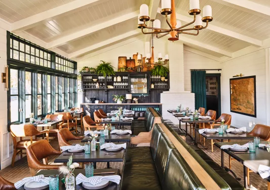 Dining area with green and brown leather sets and folded handkerchiefs on the tables