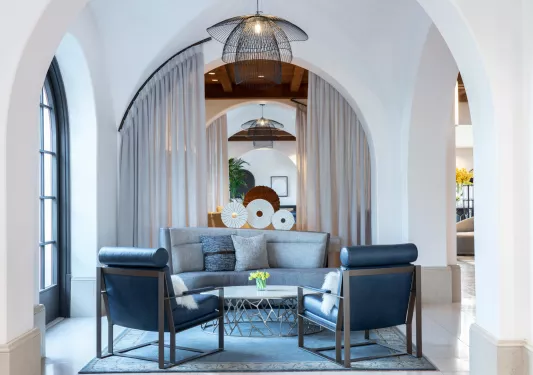 Indoor sitting lounge with blue, cushioned chairs in a white room