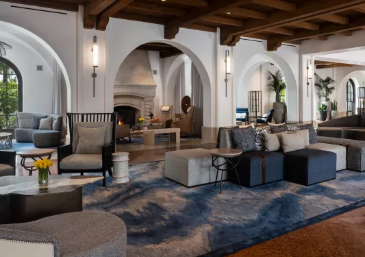 Indoor lounge with gray and navy blue cushioned chairs and a stone fireplace