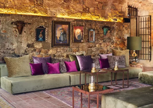 Indoor seating area with long, green sofas and purple pillows