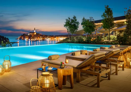 Lounge chairs next to a pool during sunset