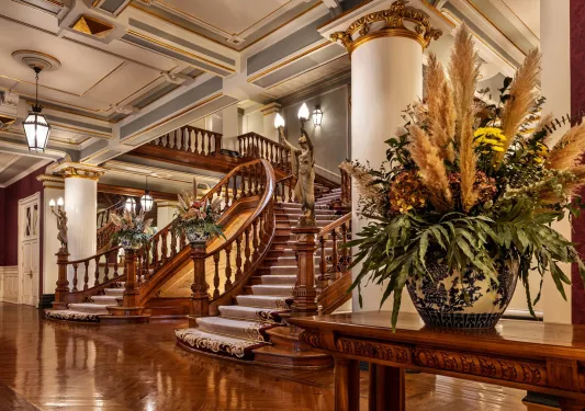 Lobby with large, wooden staircase with vases 