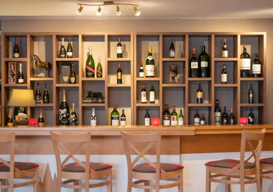 Wooden bar counter top, with bottle of wine and alcohol on the wall
