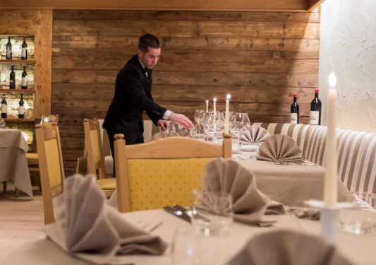 Man in a suit organizing a dining table at a restaurant