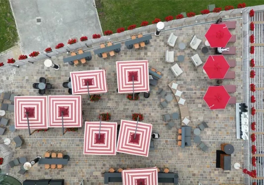 Top view of square red and pink umbrellas in a stone-floored courtyward