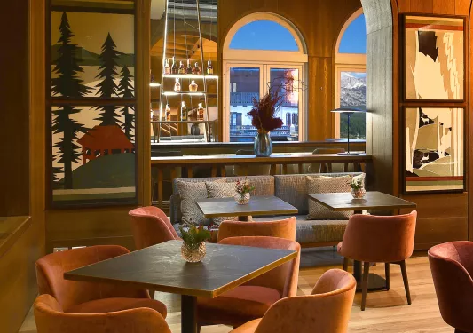 Indoor bar and lounge with square tables and cushioned chairs