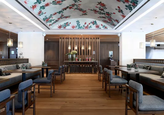 Indoor dining area with square tables and plants on each table