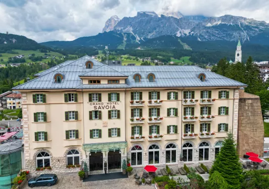 Exterior view of 4-story hotel building with mountains in the distance