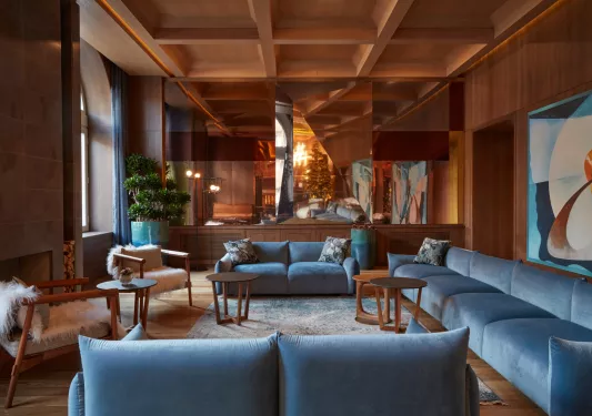 Indoor lounge with blue, cushioned seats and paintings on the wall