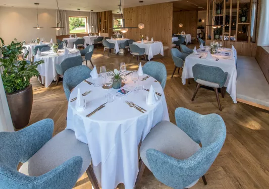 Indoor dining area with blue, cushioned chairs and folded handkerchiefs on each table