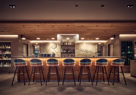 Indoor bar and lounge, with an illuminated bar counter and brown bar stools