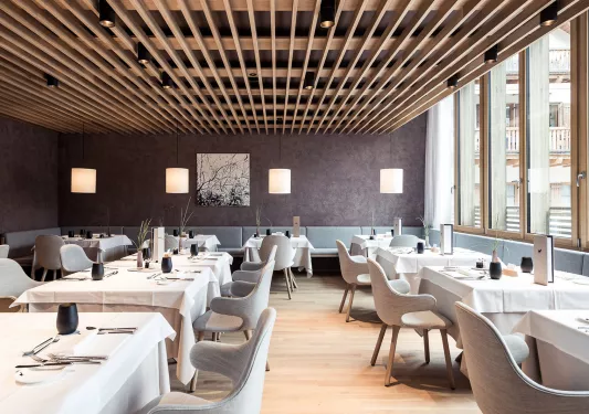 Indoor dining area with gray and white furniture and lamp shades on the ceilings
