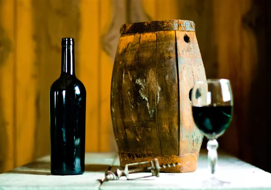 Barrell next to an open bottle of wine and a wine glass