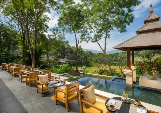 tables and chairs next to a pool