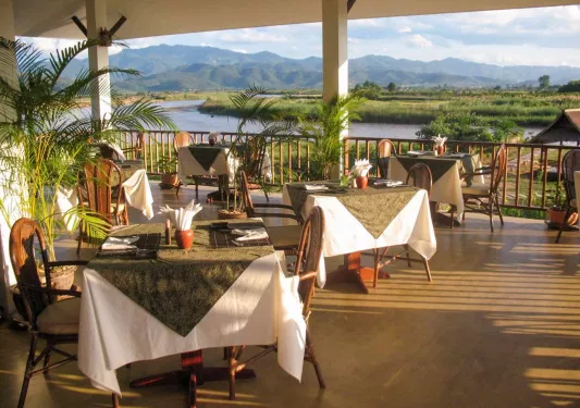 Outdoor patio dining area with a view of an open valley and lake in the distance