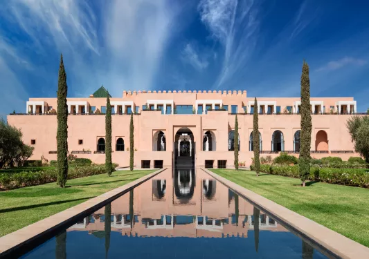 Exterior, wide view of rectangular, castle-like building with a long fountains and tall trees