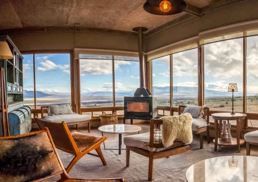 Cabin room with wooden chairs with cushions in front of a wood furnace