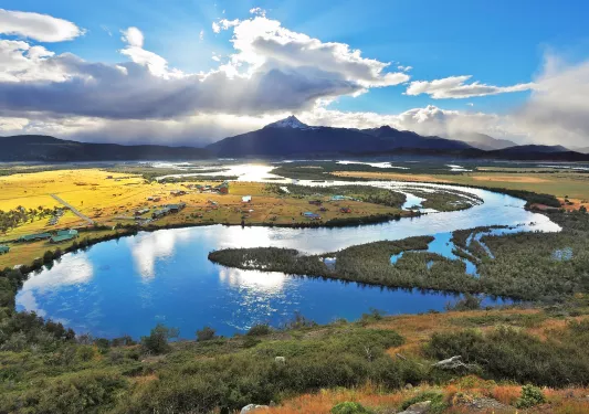 Snake-shaped lake with small houses along the open field