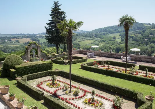 Outdoor garden with trimmed bushes, and stone barricades and statues