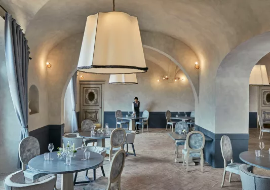 Dining area with large stone walls, and blue and gray tables and chairs