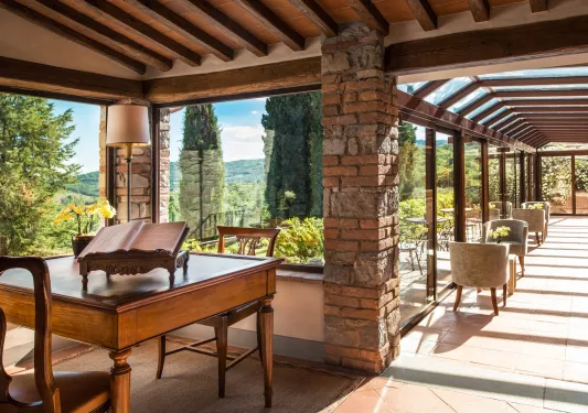 Hallway and lounge area with walls made of windows, looking out to an outdoor garden