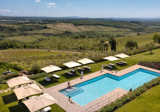 pool surrounded by lounge chairs and farmland 