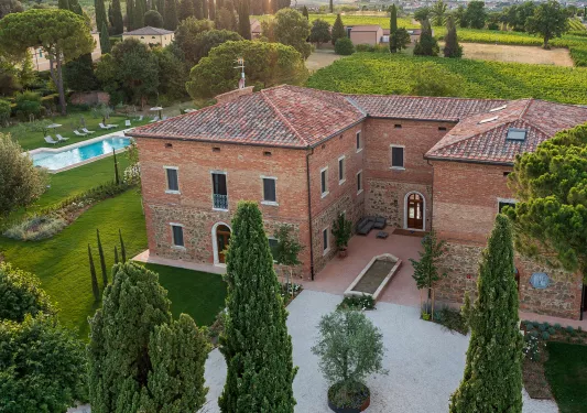 Brick and stone building with an outdoor pool on the left, surrounded by trees